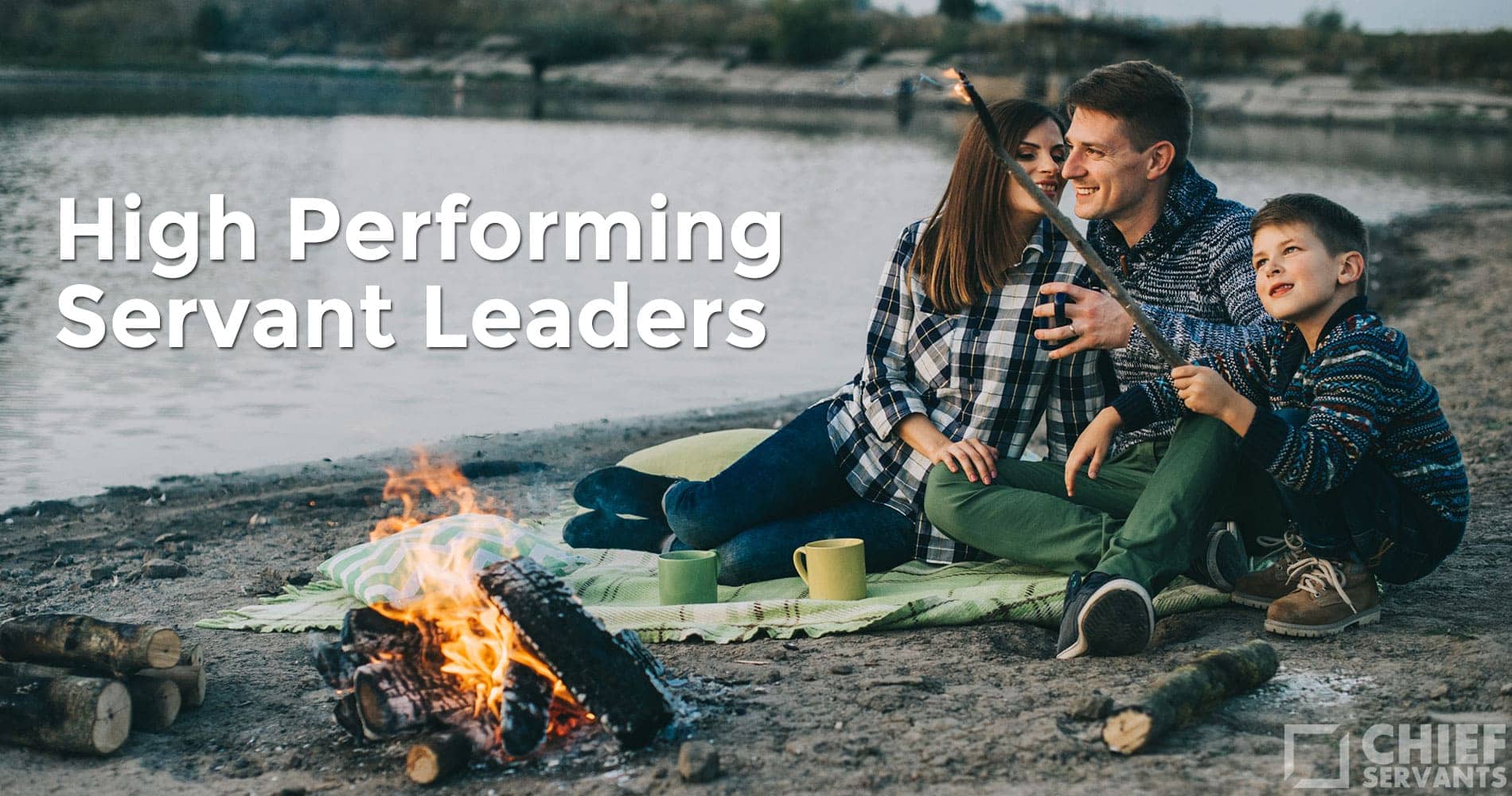 A smiling family of three sits by a lakeshore campfire roasting marshmallows, embodying servant leadership. They relax on a green blanket with mugs beside them. The text “High Performing Servant Leaders” is overlaid. Logo bottom right reads "Chief Servants.