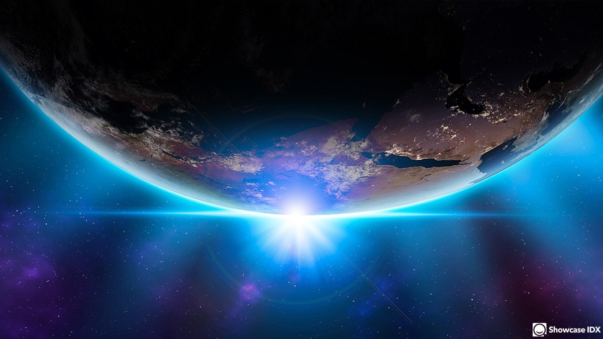 A view of Earth from space with the sun rising behind the planet, casting a bright blue glow on the horizon. Perfect inspiration to create a real estate website as vast and stunning as our world—limitless possibilities beneath a starry sky.